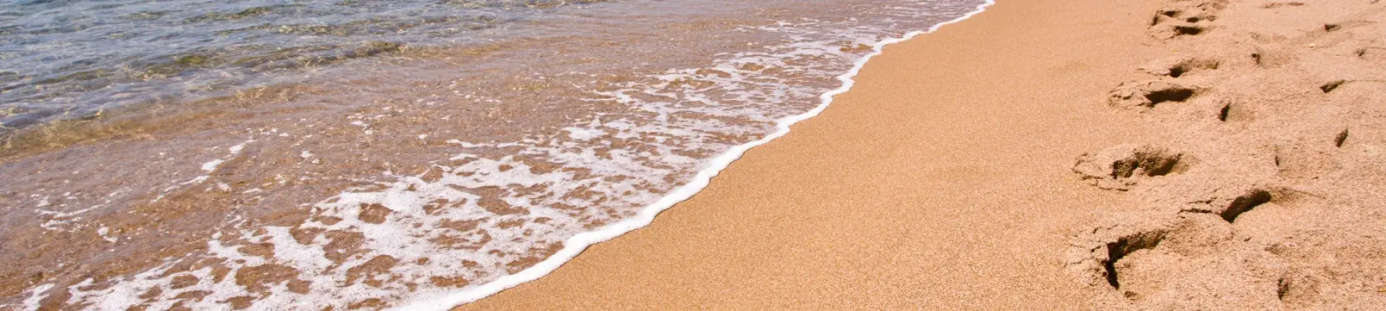 Water lapping at beach, footsteps in sand