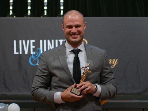 smiling man holding an award