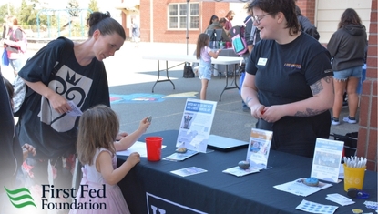Two adults and a child gather around a table at an informational fair.