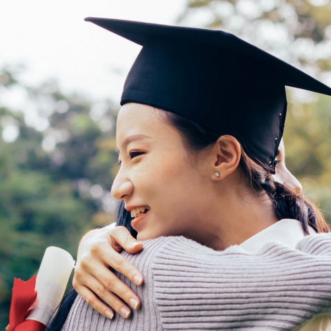 Woman in graduate cap hugging someone