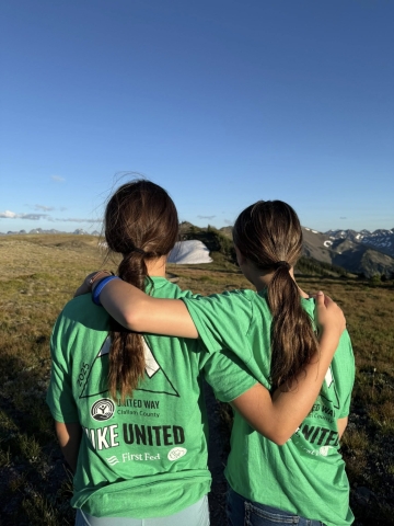 Two girls wearing Hike United t-shirts with their backs to the camera
