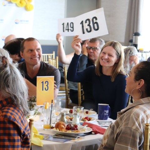 Smiling people at an event holding up bid cards