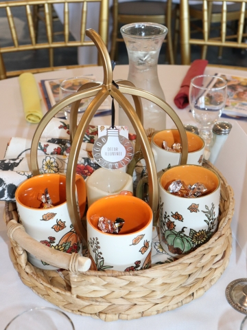 Basket of fall themed mugs sitting on a table