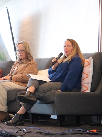woman on a stage in a comfy chair holding a microphone
