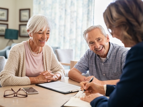 an elderly couple meeting with someone and signing papers