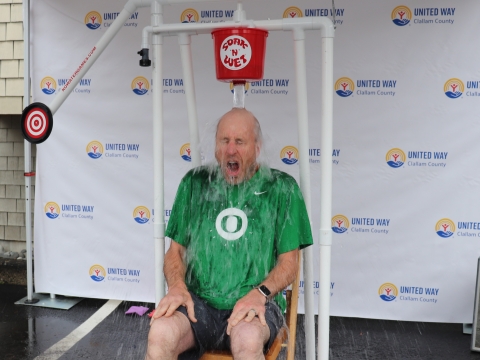 man in green shirt getting dunked by a bucket of water
