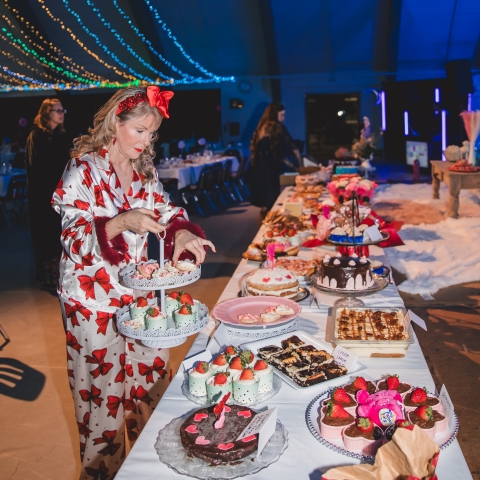 woman in pajamas placing desserts on long draped table