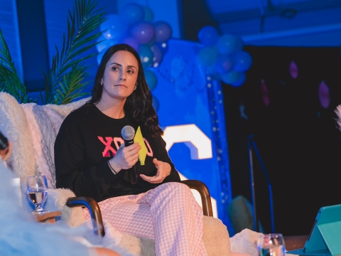 woman holding microphone sitting in chair on stage