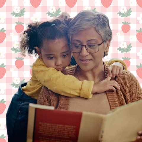 a young child hugging an older woman who is reading a book