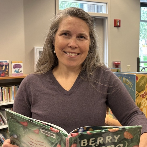 woman holding a children's book in a library