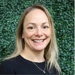 Smiling woman with blonde hair in front of green shrub